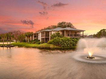 A fountain in the water with a house in the background